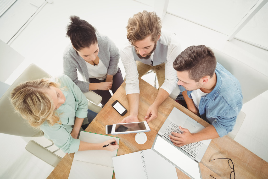 Overhead view of business people with digital tablet while sitting at desk in office