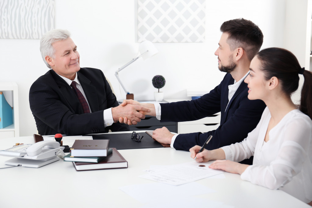 a man shaking hands with another man while a woman takes notes