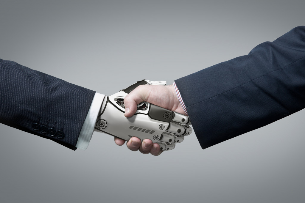 a robotic hand shaking hands with a hu,an hand both in suits